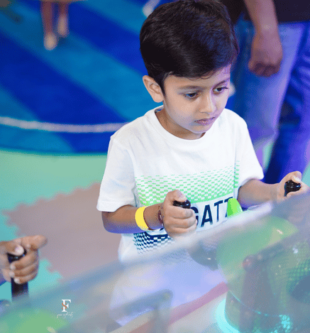 Child enjoying an exciting arcade game at Wooray Delhi, holding the game controls during play.